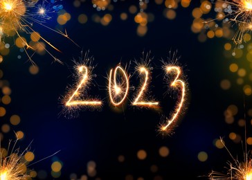 Image of 2023 silhouette made of sparkler on dark background. Greeting card design