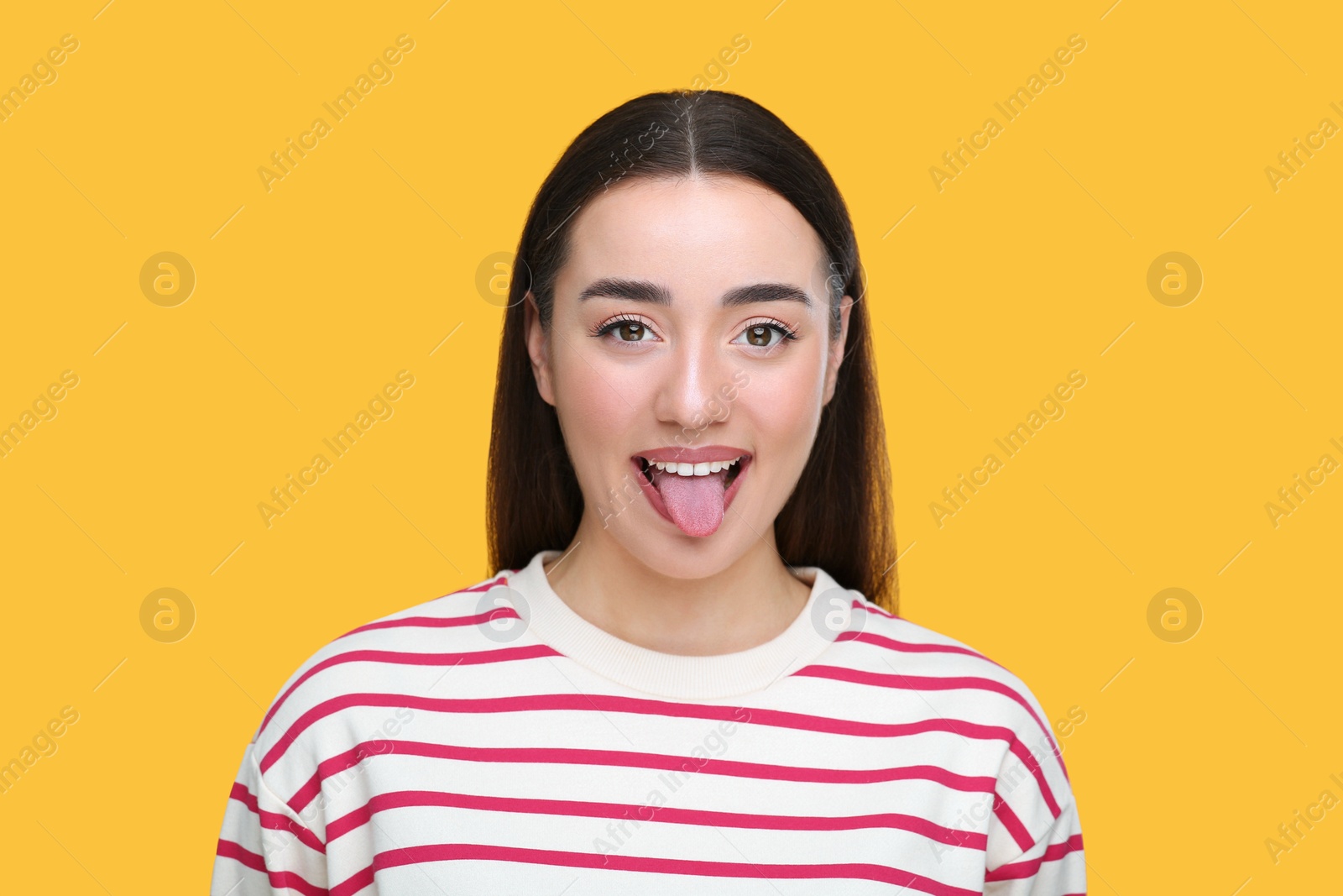 Photo of Happy woman showing her tongue on orange background