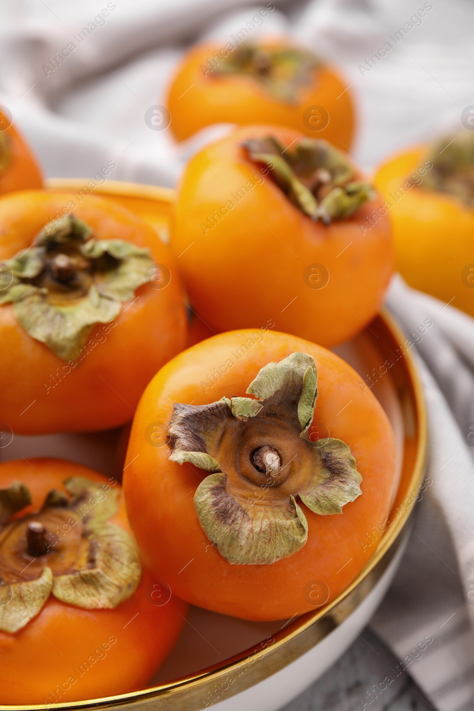 Photo of Bowl with delicious ripe juicy persimmons, closeup