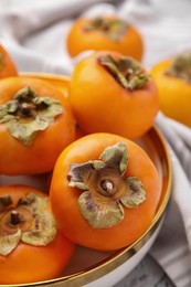 Photo of Bowl with delicious ripe juicy persimmons, closeup