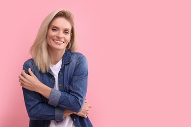 Photo of Portrait of smiling middle aged woman with blonde hair on pink background. Space for text