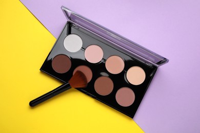 Photo of Contouring palette with brush on color background, top view. Professional cosmetic product