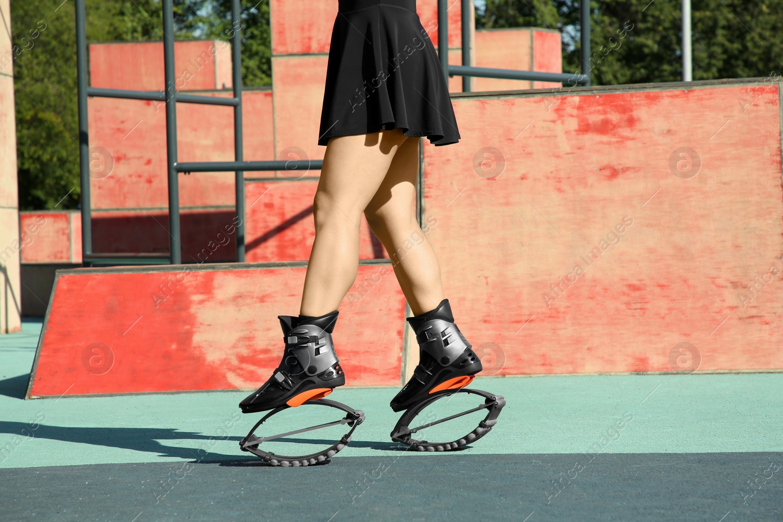 Photo of Woman doing exercises in kangoo jumping boots in workout park, closeup