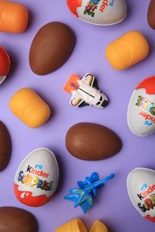 Sveti Vlas, Bulgaria - June 30, 2023: Kinder Surprise Eggs, toys and plastic capsules on violet background, flat lay