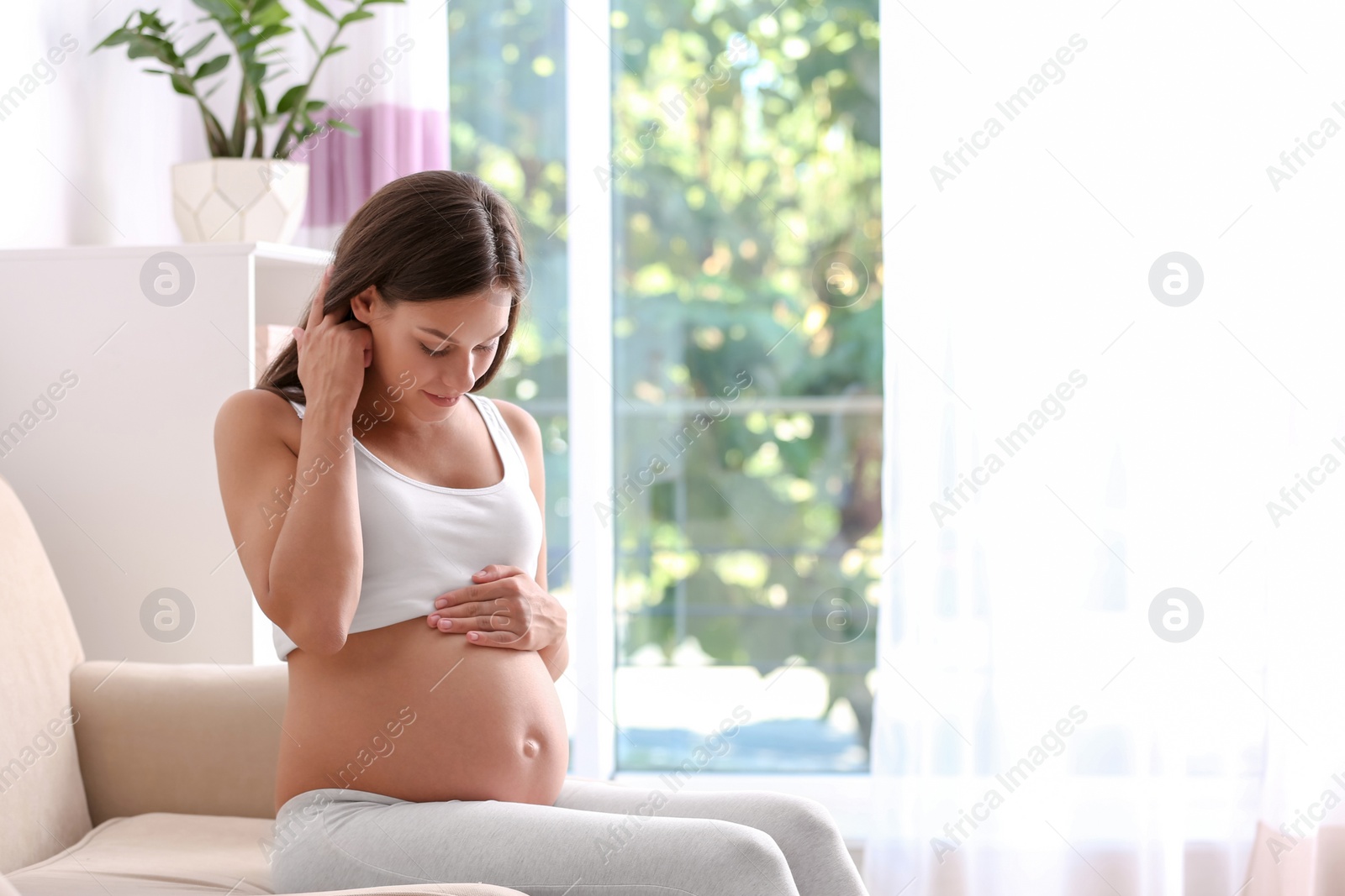 Photo of Pregnant woman sitting on sofa at home