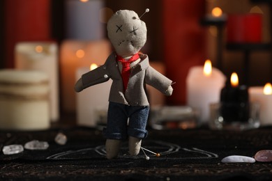 Photo of Voodoo doll pierced with pins on table in dark room. Curse ceremony