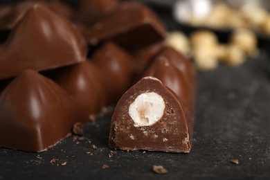 Photo of Tasty chocolate bars with nuts on black table, closeup