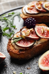 Photo of Bruschettas with cream cheese, figs and blackberries on slate plate, closeup