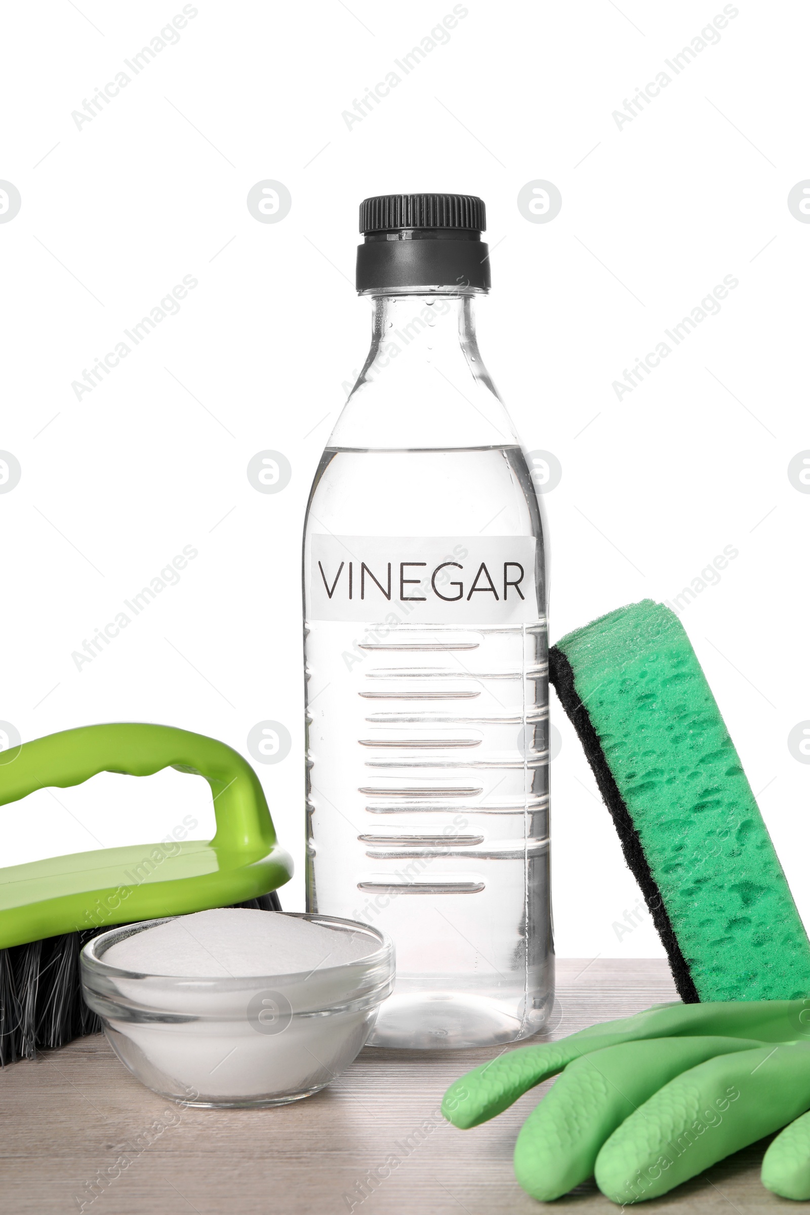 Photo of Natural cleaning products. Vinegar in bottle, baking soda, glove, sponge and brush on light wooden table against white background