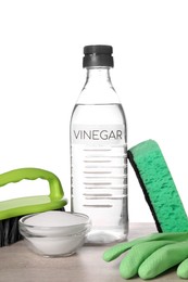 Photo of Natural cleaning products. Vinegar in bottle, baking soda, glove, sponge and brush on light wooden table against white background