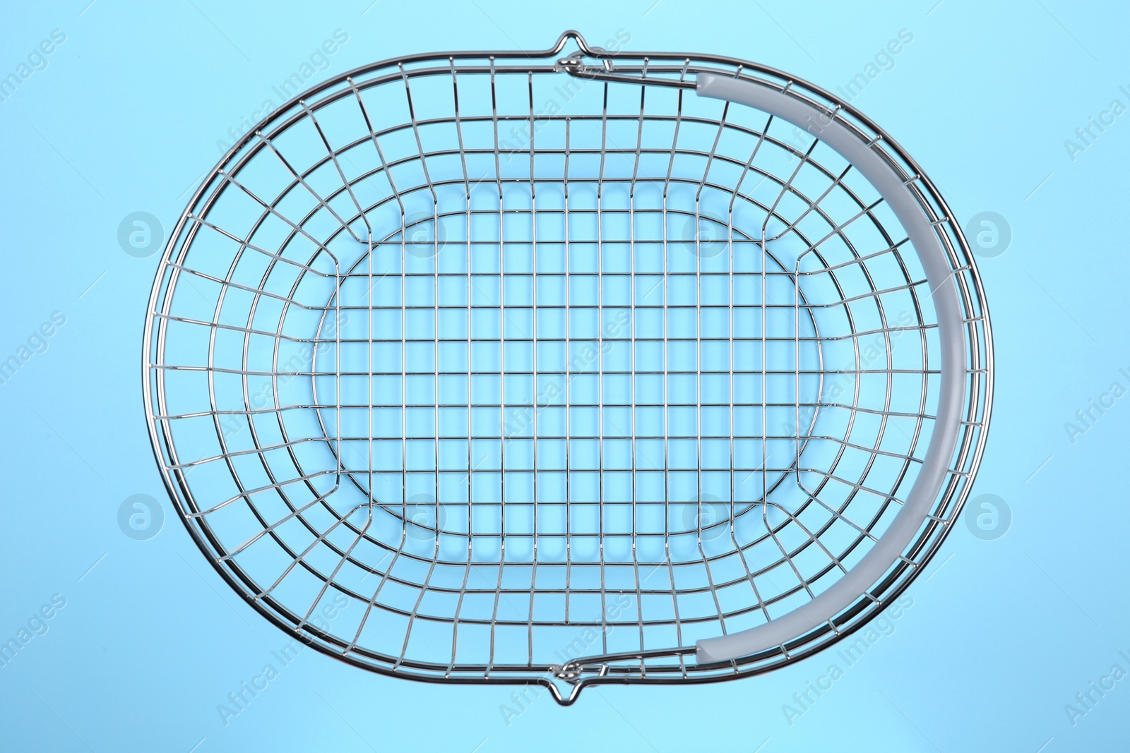 Photo of Empty metal shopping basket on light blue background, top view