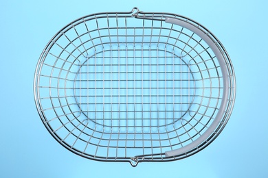 Photo of Empty metal shopping basket on light blue background, top view