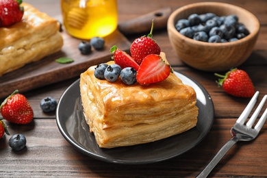 Photo of Fresh delicious puff pastry with sweet berries on wooden table