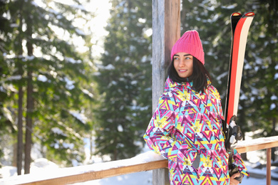 Photo of Young woman with ski wearing winter sport clothes in forest. Space for text