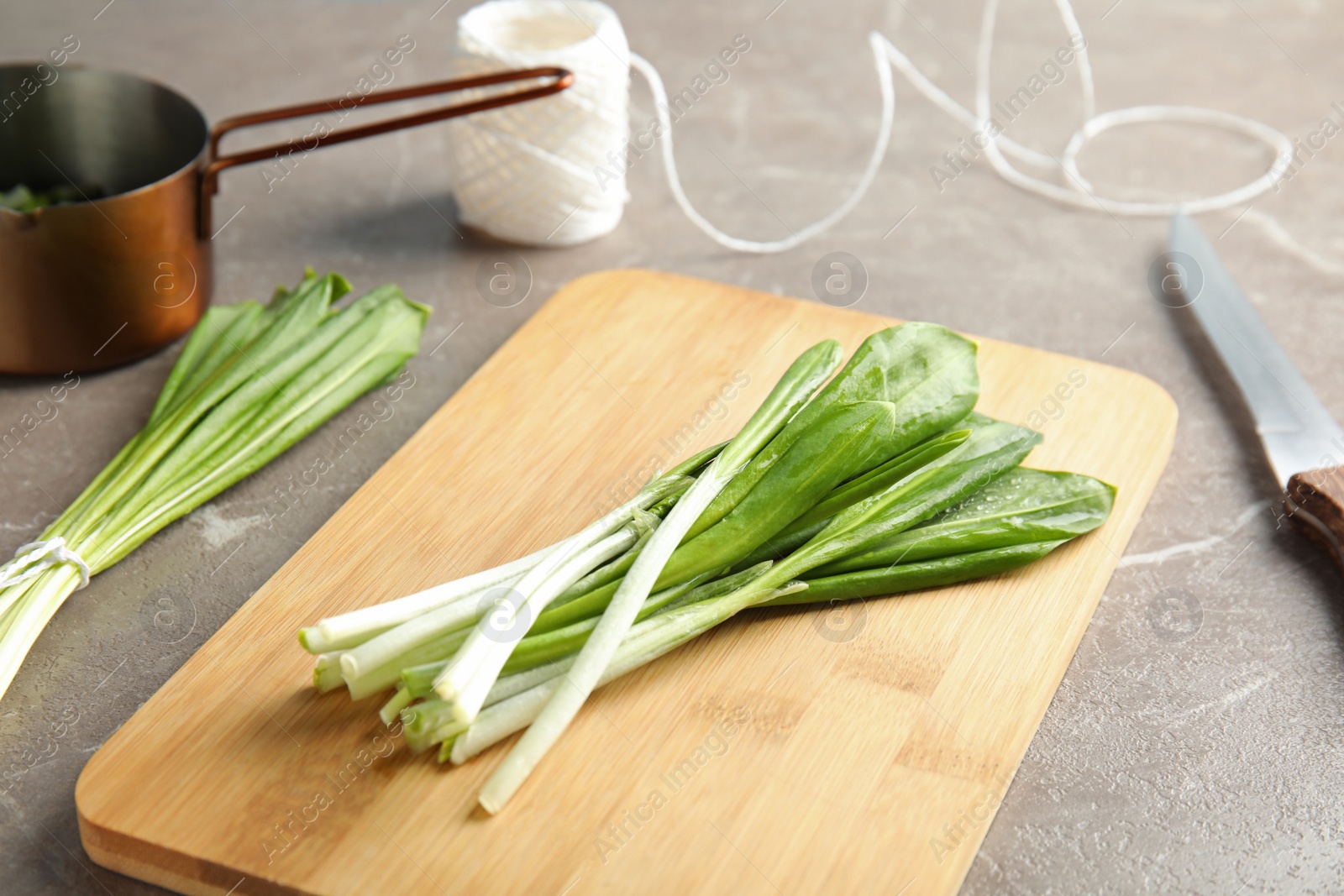 Photo of Board with wild garlic or ramson on grey table, closeup