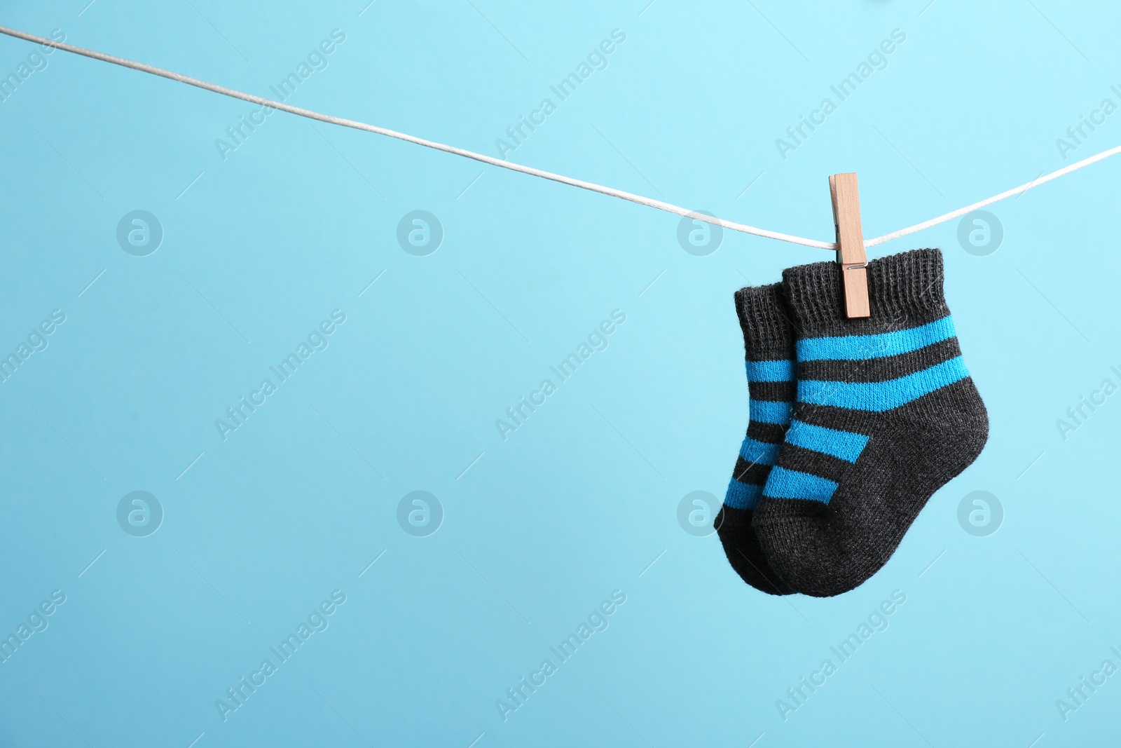 Photo of Small socks hanging on washing line against color background, space for text. Baby accessories