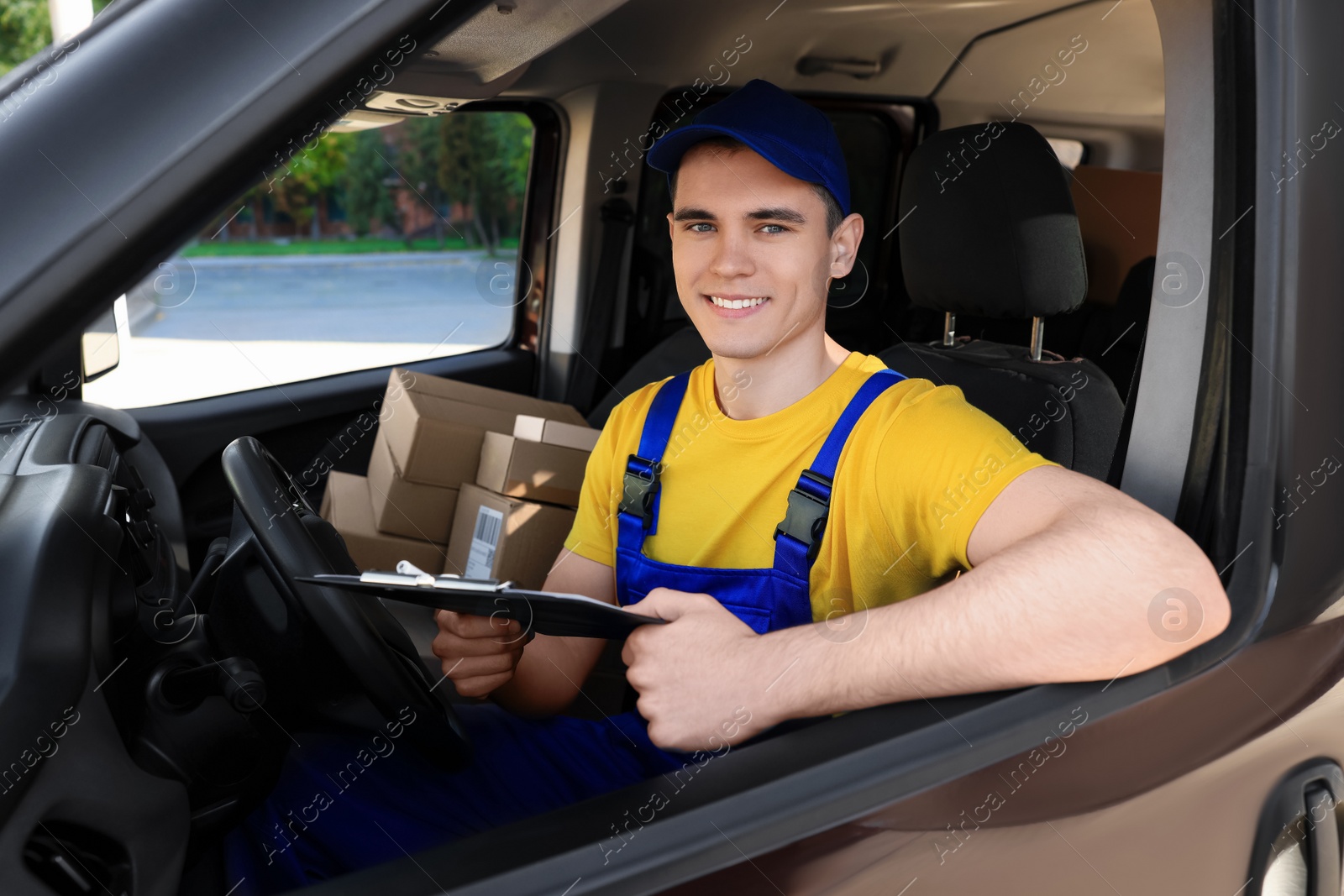 Photo of Courier with clipboard checking packages in car