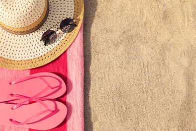 Photo of Beach towel with slippers, straw hat and sunglasses on sand, flat lay. Space for text