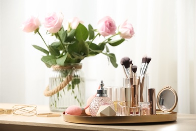 Photo of Different makeup products and accessories on dressing table in room interior