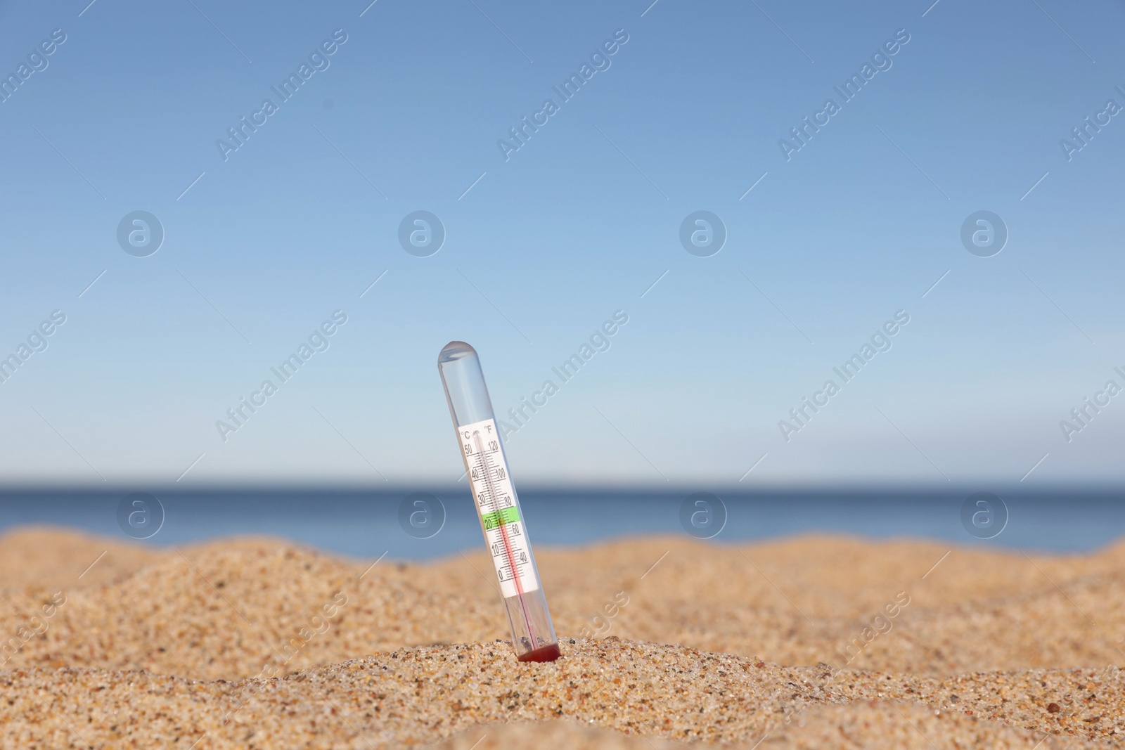 Photo of Weather thermometer in sand near sea, space for text