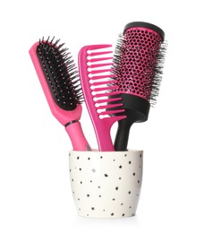 Hairbrushes and comb in holder on white background