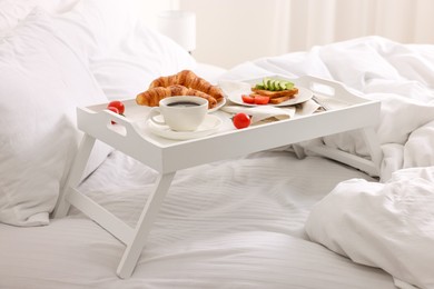 Photo of Good morning. Tray with tasty breakfast on bed at home