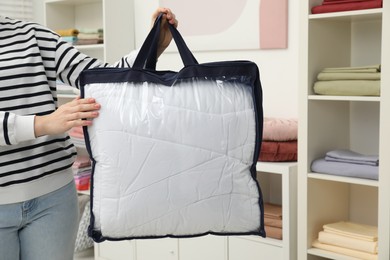 Photo of Woman holding bag with duvet in home textiles store, closeup. Space for text