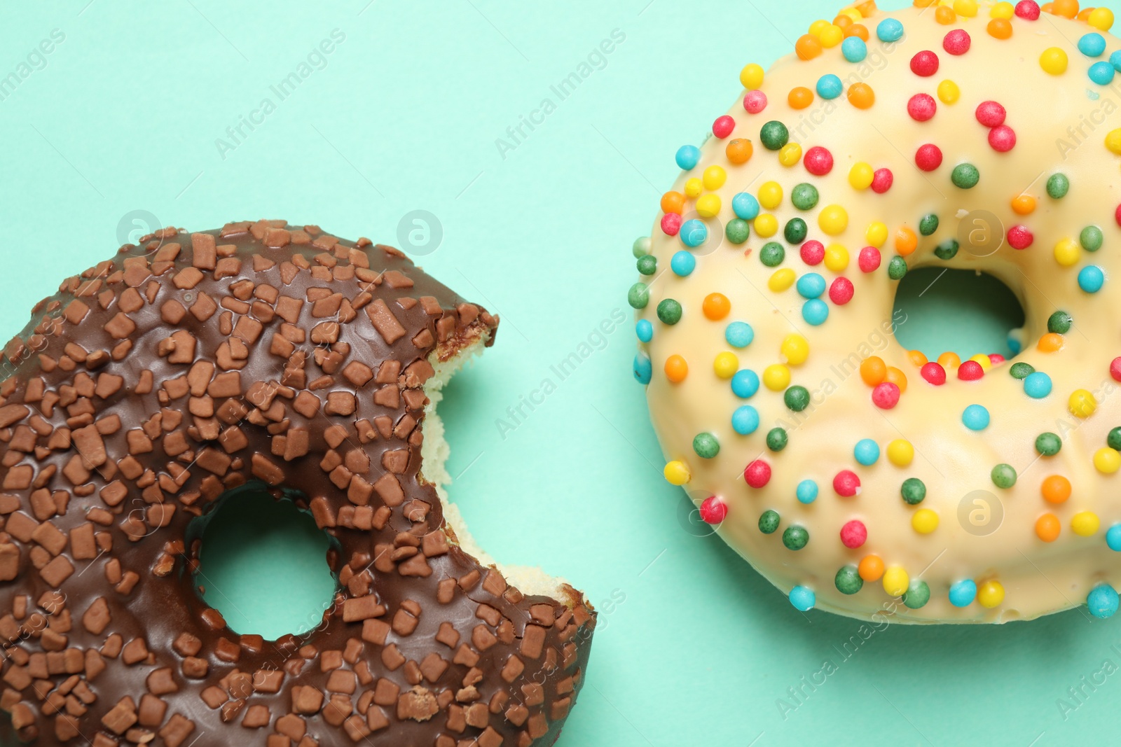 Photo of Delicious glazed donuts on turquoise background, flat lay