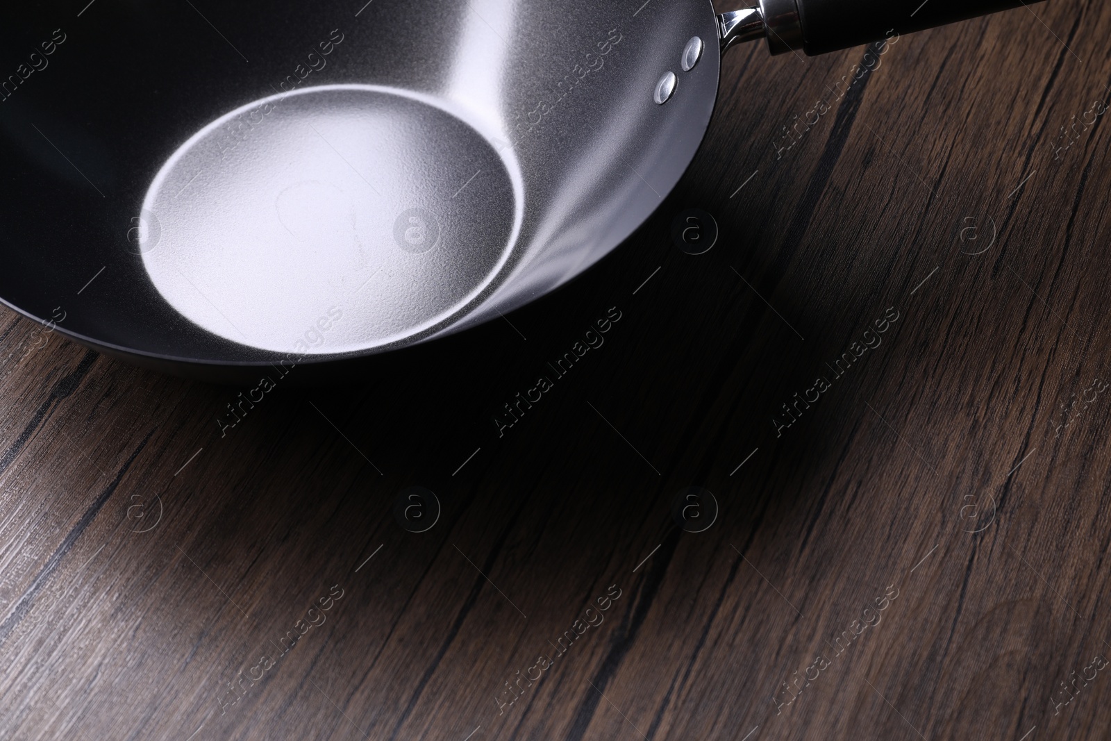 Photo of Empty iron wok on wooden table, closeup. Chinese cookware