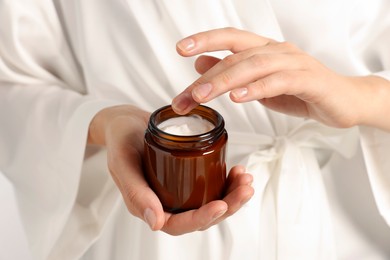Photo of Woman holding jar of hand cream, closeup