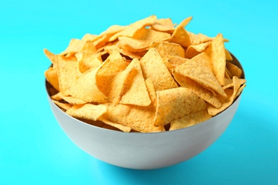 Tasty mexican nachos chips in metal bowl on blue background