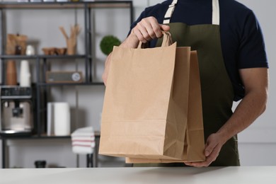 Photo of Worker with paper bags at counter in cafe, closeup. Space for text