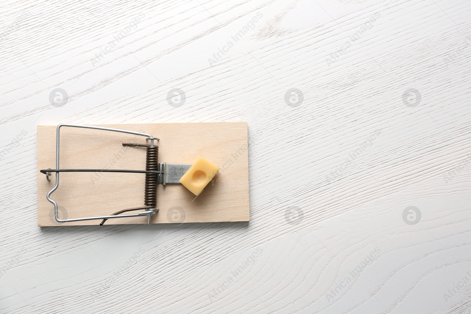 Photo of Mousetrap with piece of cheese and space for text on white wooden background, top view. Pest control