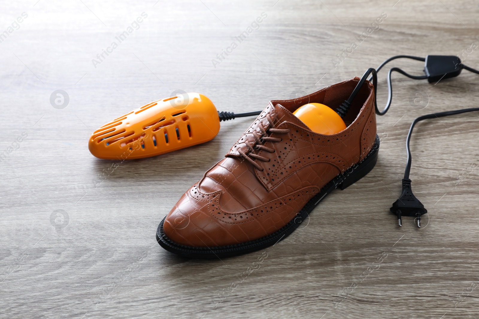 Photo of Stylish shoe with modern electric footwear dryer on wooden background