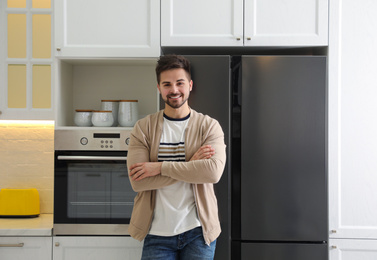 Photo of Happy young man near refrigerator in kitchen