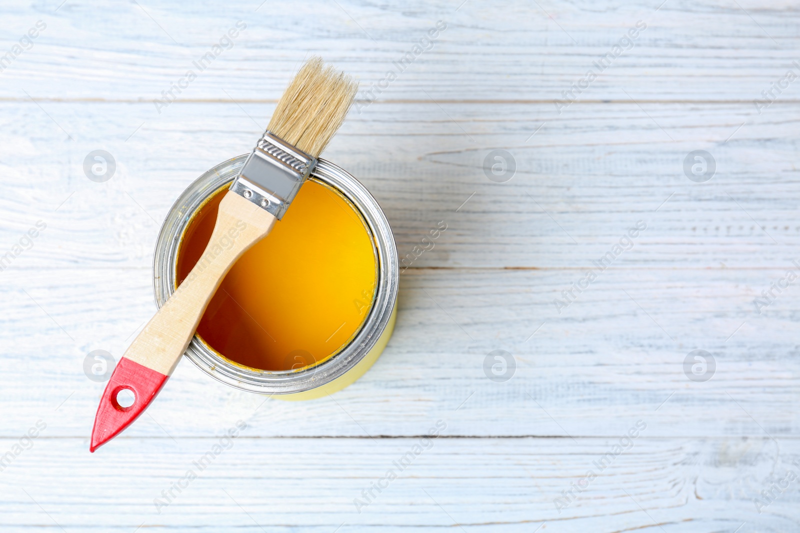 Photo of Tin can with paint and brush on wooden background, top view