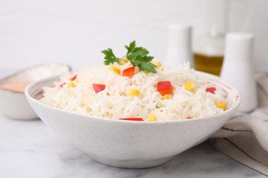 Photo of Bowl of delicious rice with vegetables and parsley on light table, closeup