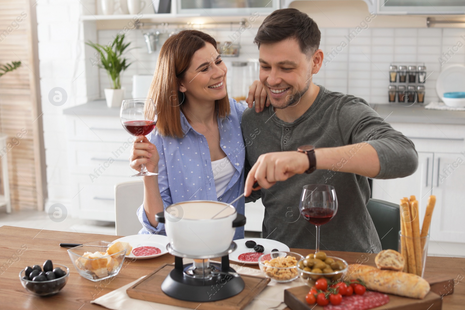 Photo of Happy couple enjoying fondue dinner at home