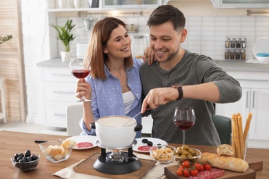 Happy couple enjoying fondue dinner at home