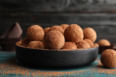 Plate of chocolate truffles powdered with cocoa on wooden table