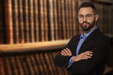 Successful lawyer in glasses near shelves with books, space for text