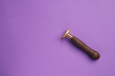 Photo of One stamp tool with wooden handle on purple background, top view. Space for text