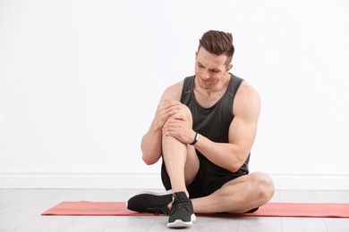 Photo of Male athlete suffering from knee pain during training indoors