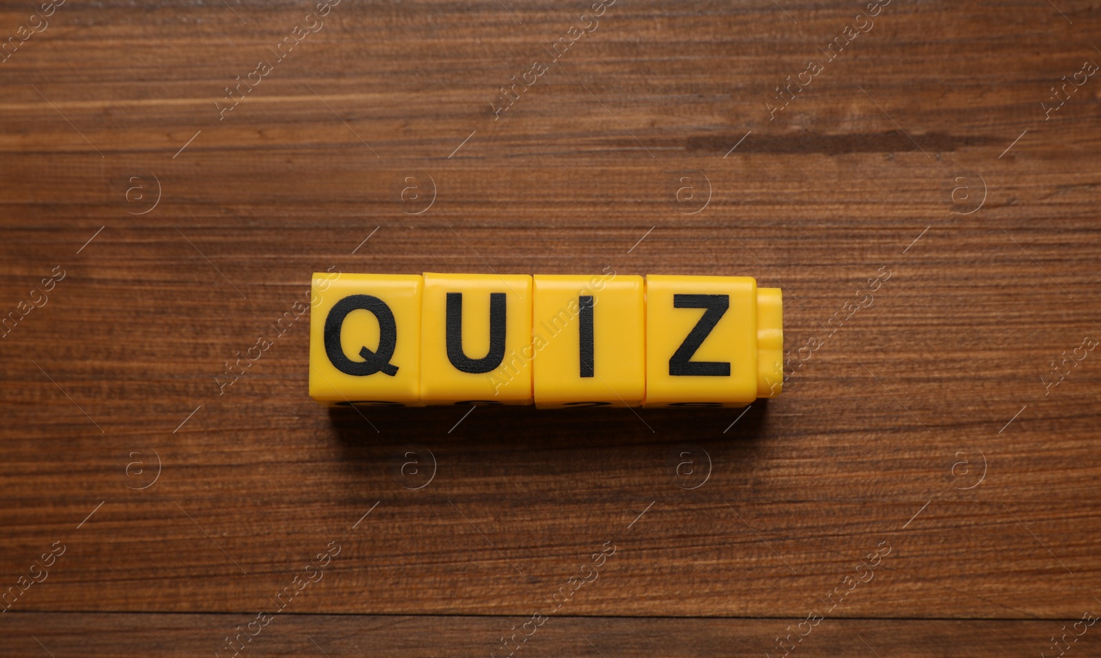 Photo of Yellow cubes with word Quiz on wooden table, flat lay