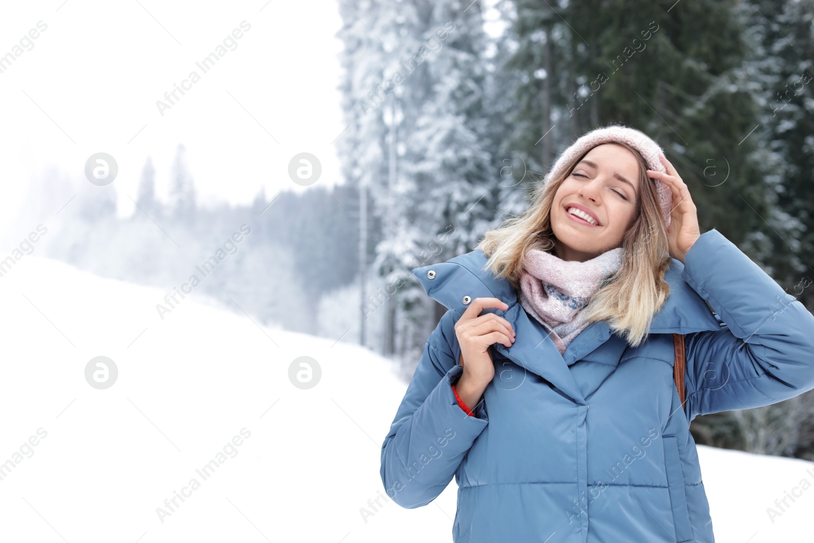 Photo of Happy young woman in warm clothes outdoors, space for text. Winter vacation