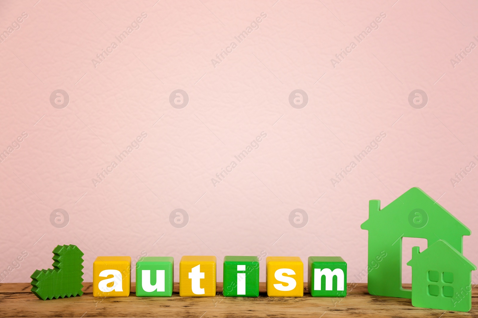 Photo of Wooden houses and cubes with word "Autism" on table