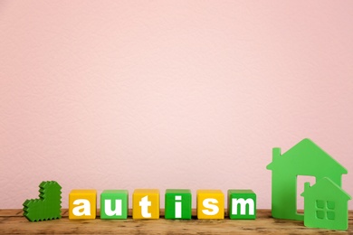 Wooden houses and cubes with word "Autism" on table