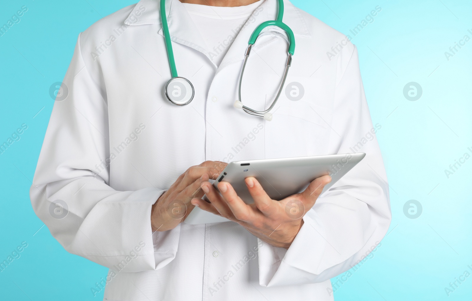 Photo of Male doctor with stethoscope and tablet PC on color background, closeup. Medical object