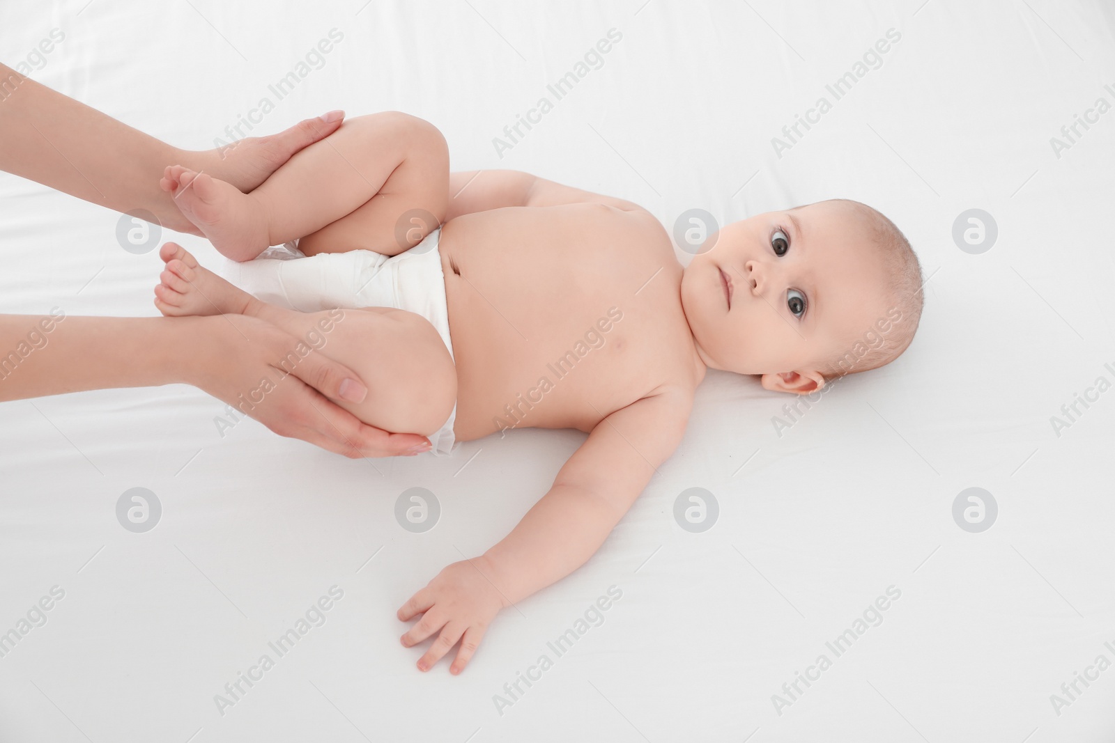 Photo of Mother and her cute child on white bed, above view. Baby massage and exercises