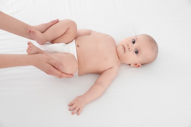 Mother and her cute child on white bed, above view. Baby massage and exercises